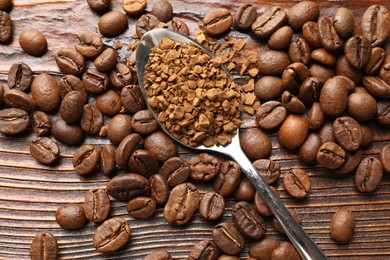 Photo of Spoon with instant coffee and beans on wooden table, flat lay