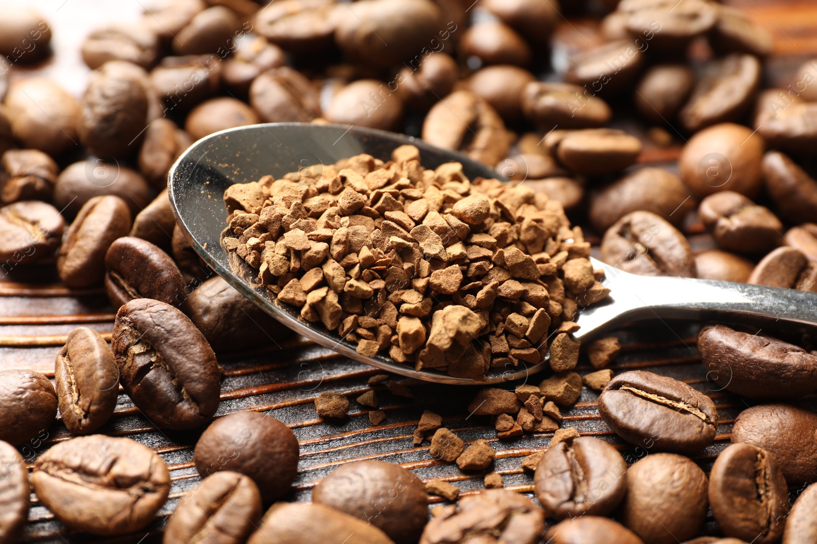 Spoon with instant coffee and beans on wooden table, closeup Photo of Spoon with instant coffee and beans on wooden table, closeup