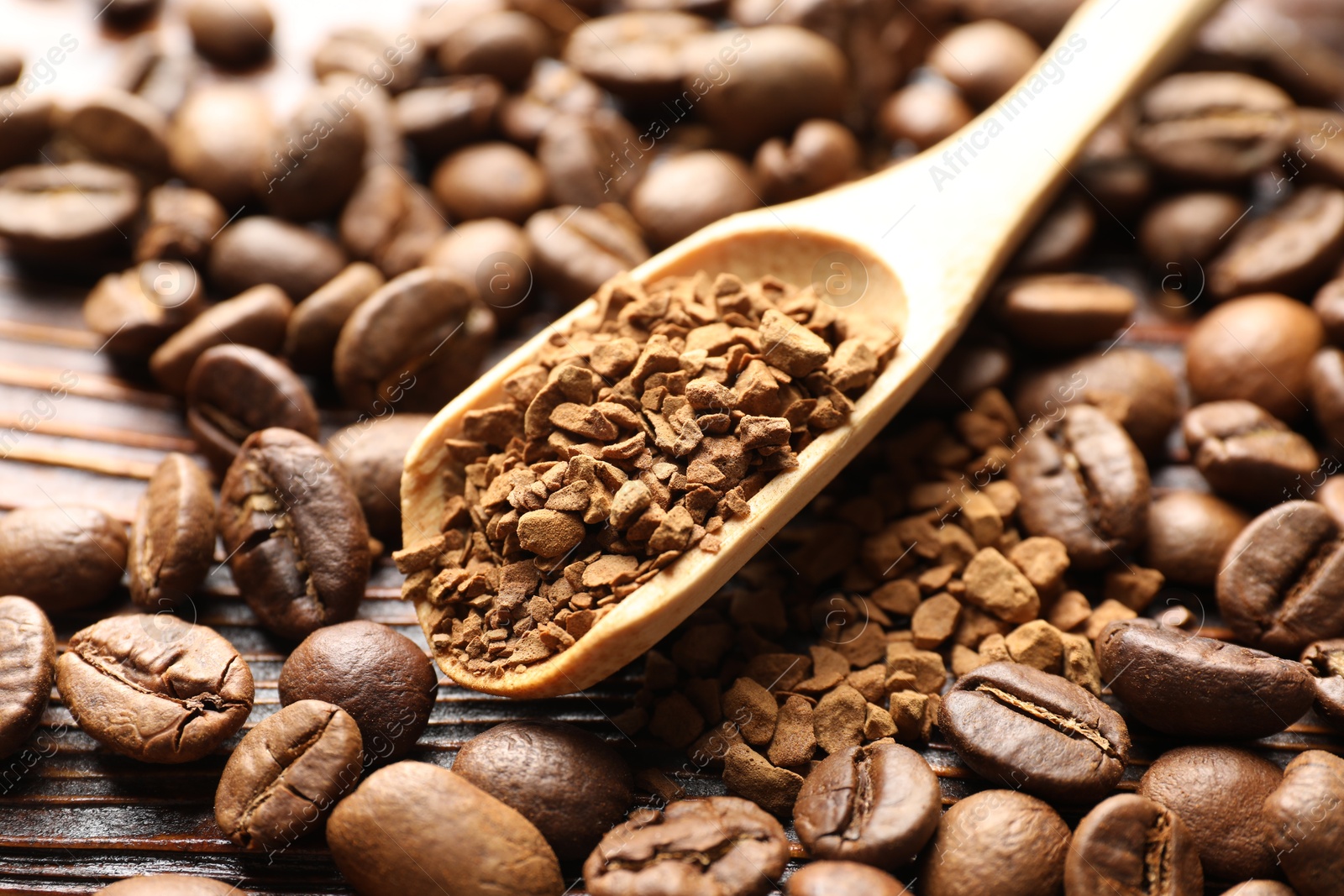 Spoon with instant coffee and beans on wooden table, closeup Photo of Spoon with instant coffee and beans on wooden table, closeup