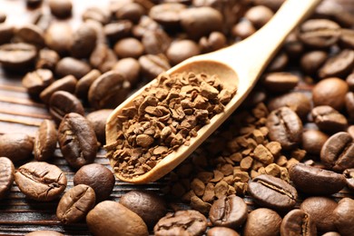 Photo of Spoon with instant coffee and beans on wooden table, closeup