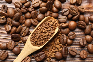Photo of Spoon with instant coffee and beans on wooden table, flat lay