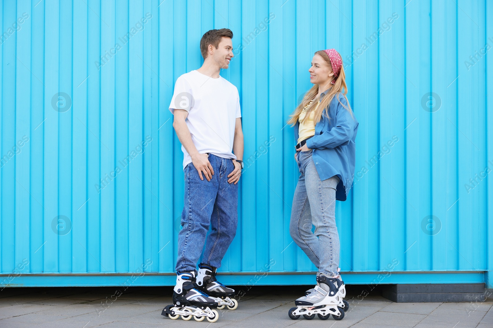 Happy couple with roller skates near light blue wall outdoors Photo of Happy couple with roller skates near light blue wall outdoors