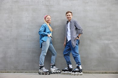 Photo of Happy couple with roller skates near gray wall outdoors