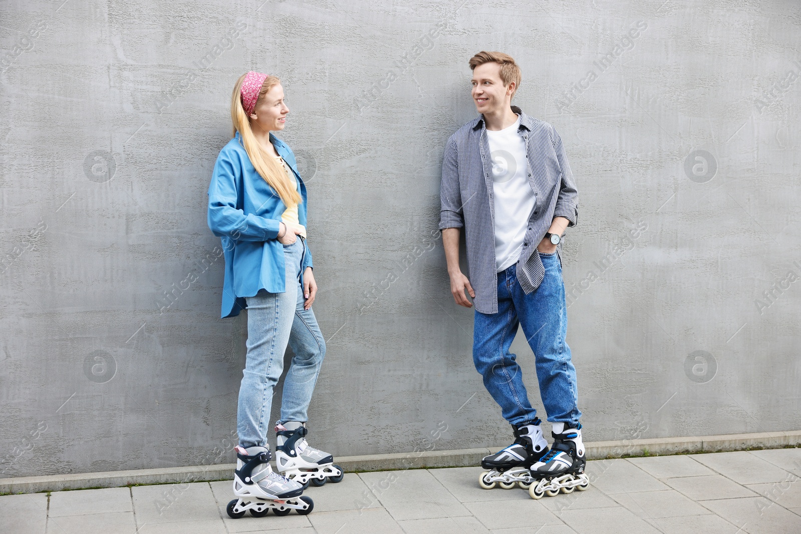 Happy couple with roller skates near gray wall outdoors Photo of Happy couple with roller skates near gray wall outdoors