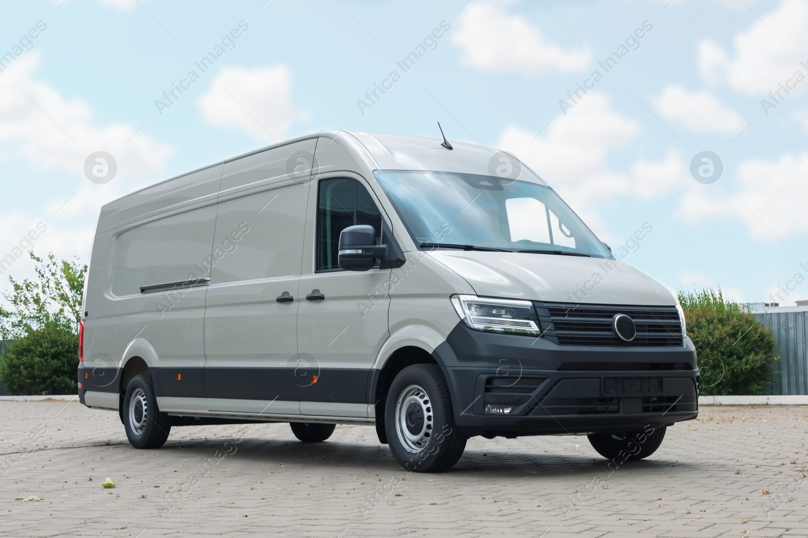 One white minibus parked on paved road outdoors Photo of One white minibus parked on paved road outdoors