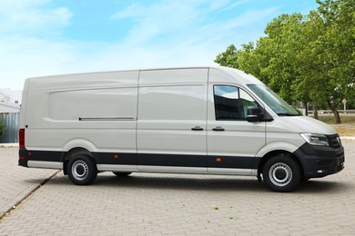Photo of One white minibus parked on paved road outdoors
