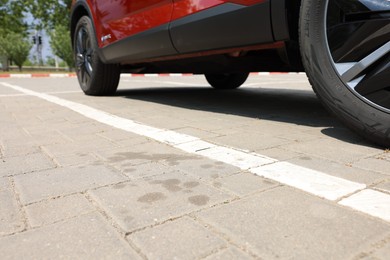 Photo of Stains of motor oil near car on paved road outdoors, closeup