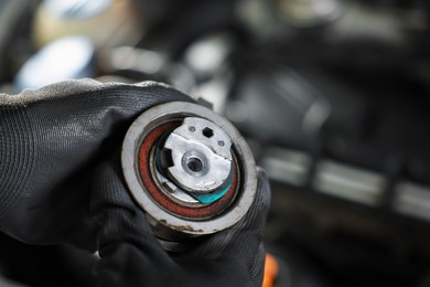 Photo of Auto part. Professional mechanic with idler-wheel near open hood of car indoors, closeup. Space for text