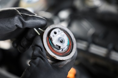 Photo of Auto part. Professional mechanic with idler-wheel near open hood of car indoors, closeup. Space for text