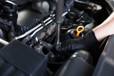 Photo of Auto parts. Professional mechanic with torque wrench fixing car indoors, closeup