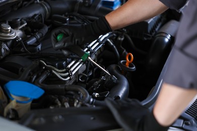 Photo of Auto parts. Professional mechanic with screwdriver fixing car indoors, closeup