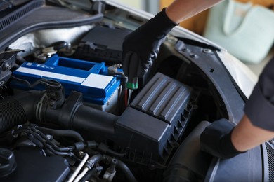 Photo of Auto parts. Professional mechanic with screwdriver fixing car indoors, closeup