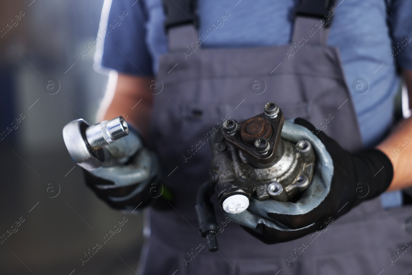 Auto part. Professional mechanic with hydraulic pump and socket wrench indoors, closeup Photo of Auto part. Professional mechanic with hydraulic pump and socket wrench indoors, closeup