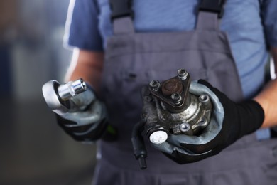 Photo of Auto part. Professional mechanic with hydraulic pump and socket wrench indoors, closeup