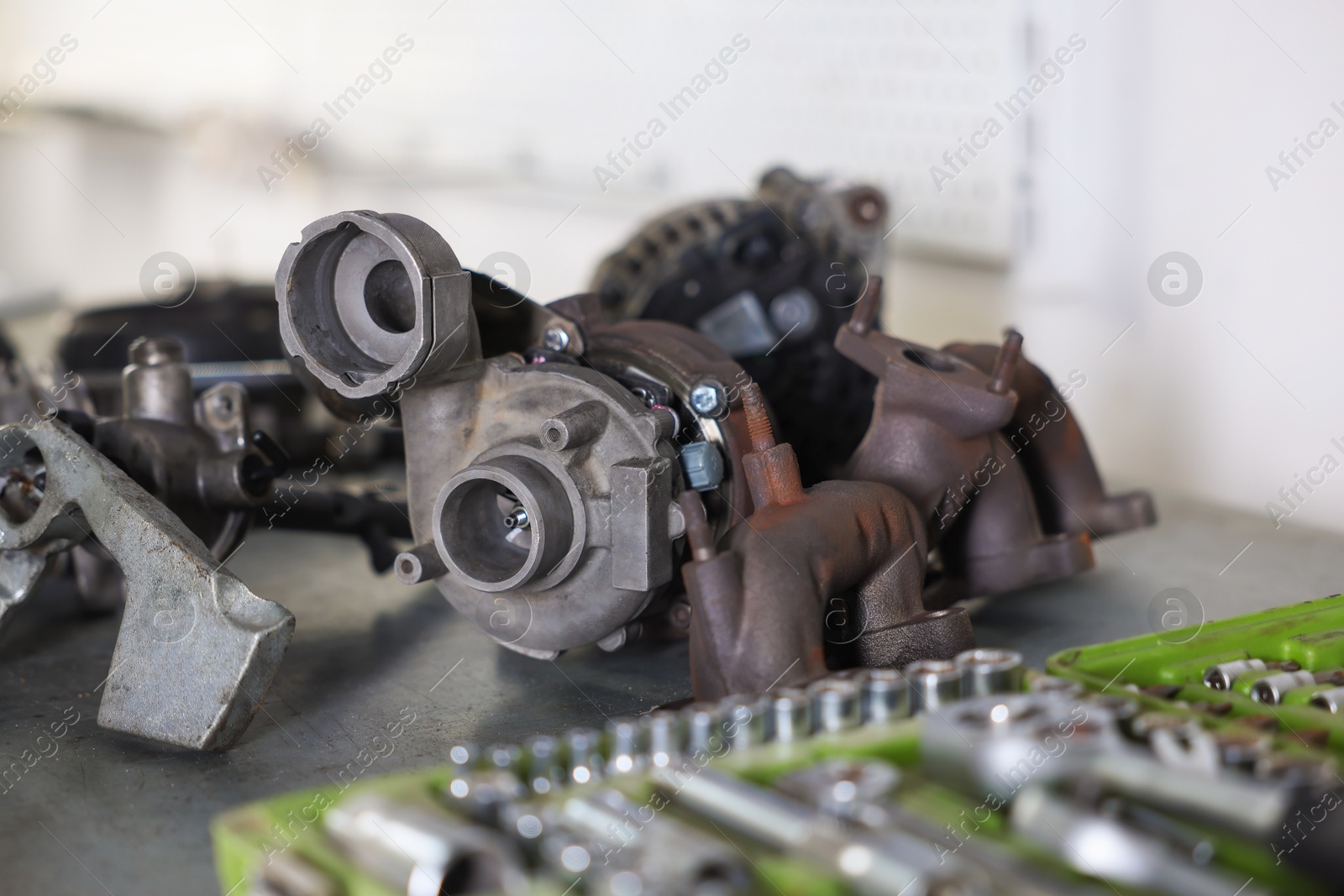 Different auto parts and tools on grey table indoors, closeup Photo of Different auto parts and tools on grey table indoors, closeup