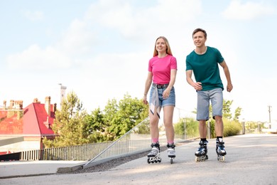 Photo of Happy couple roller skating together on street. Space for text