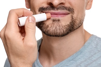 Photo of Man applying lip balm onto his lips on white background, closeup