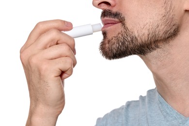 Photo of Man applying lip balm onto his lips on white background, closeup