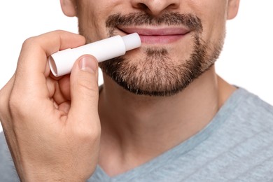 Photo of Man applying lip balm onto his lips on white background, closeup