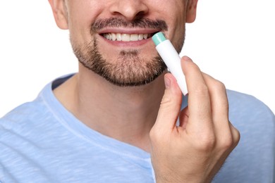 Photo of Smiling man applying lip balm onto his lips on white background, closeup