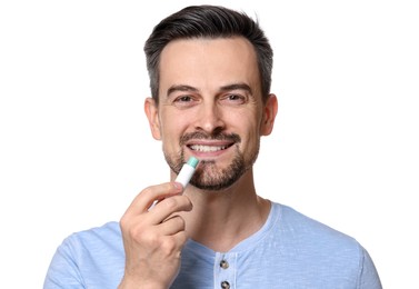 Photo of Smiling man applying lip balm onto his lips on white background