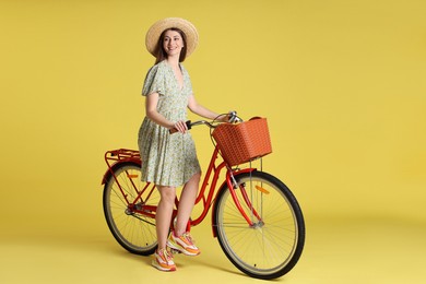 Photo of Smiling woman in hat and bicycle with basket on light green background