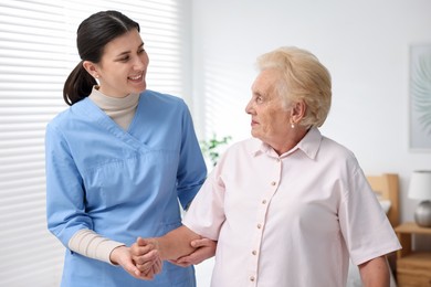 Photo of Nurse assisting senior woman indoors. Home health care service