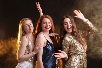 Photo of Beautiful women with different hair colors on dark background with smoke