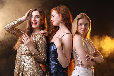 Photo of Beautiful women with different hair colors on dark background with smoke