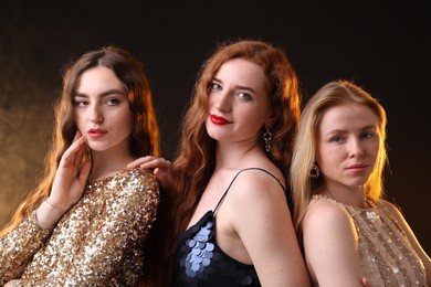 Photo of Beautiful women with different hair colors on dark background with smoke