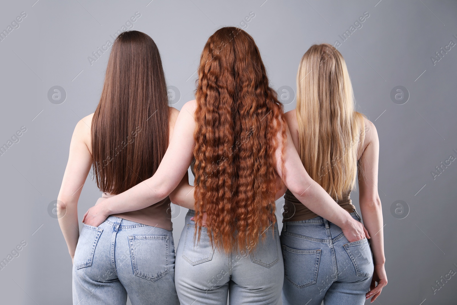 Women with different hair colors on grey background, back view Photo of Women with different hair colors on grey background, back view