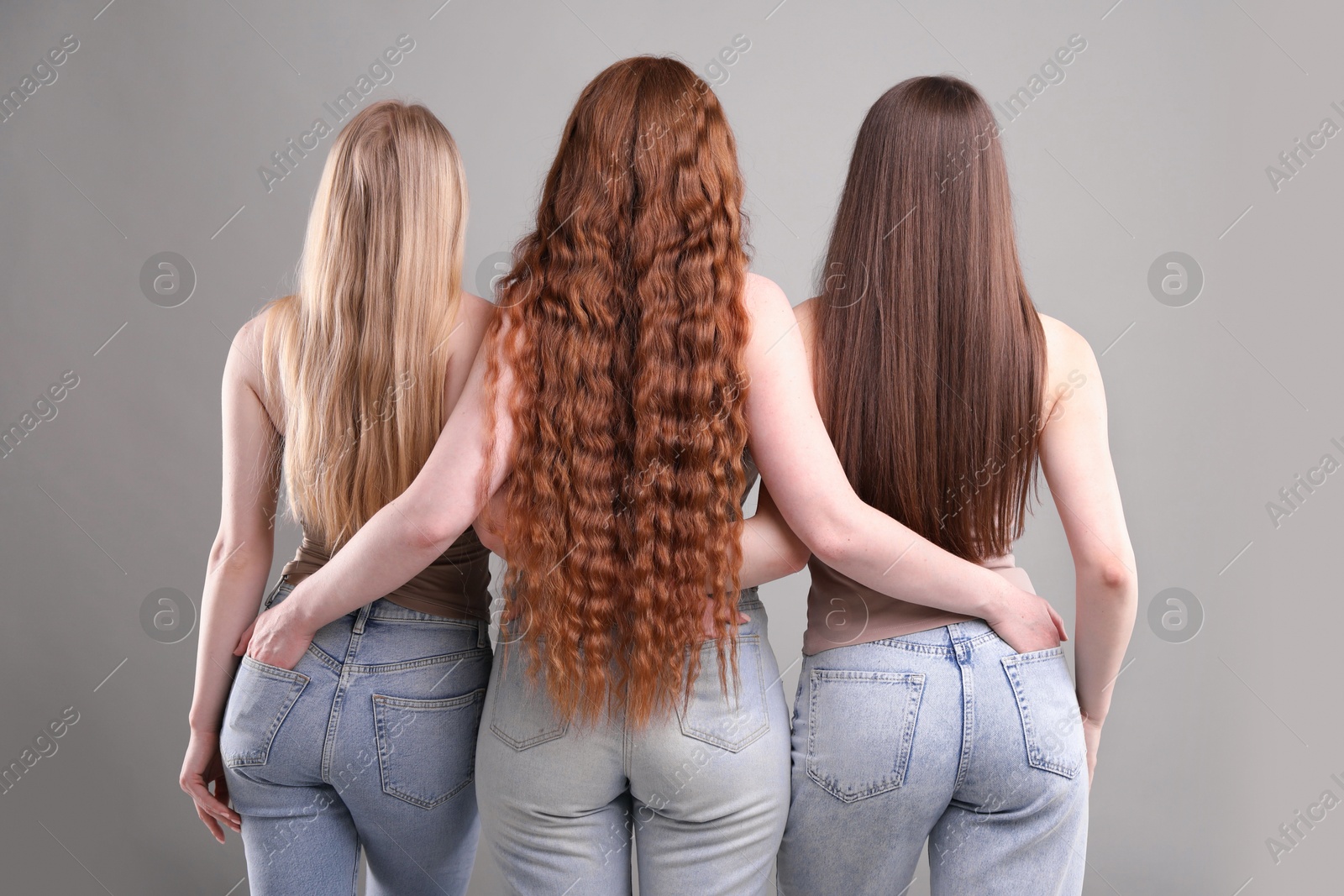 Women with different hair colors on grey background, back view Photo of Women with different hair colors on grey background, back view