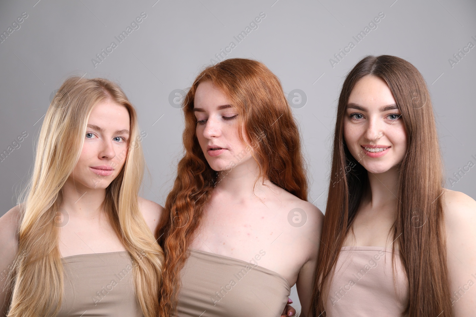 Beautiful women with different hair colors on grey background Photo of Beautiful women with different hair colors on grey background