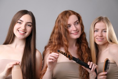 Photo of Beautiful women with different hair colors holding curling iron, shampoo and brush on grey background
