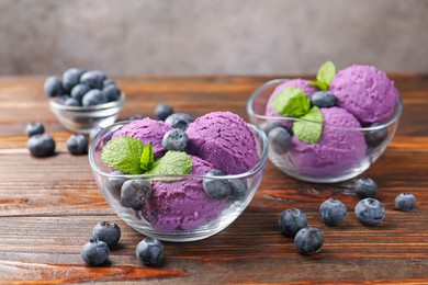 Photo of Tasty sorbet with blueberries and mint served on wooden table, closeup