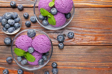 Photo of Tasty sorbet with blueberries and mint served on wooden table, flat lay. Space for text