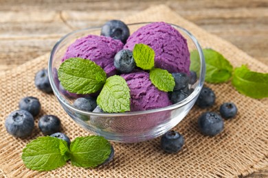 Photo of Tasty sorbet with blueberries and mint served on wooden table, closeup