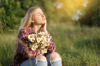 Photo of Beautiful woman with wildflowers enjoying summer day in meadow. Space for text