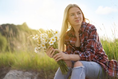 Photo of Beautiful woman with bouquet of wildflowers in meadow. Space for text