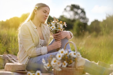 Photo of Beautiful woman with bouquet of wildflowers on blanket in meadow