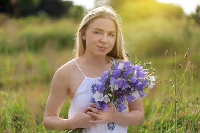 Photo of Beautiful woman with bouquet of wildflowers enjoying sunny day in meadow