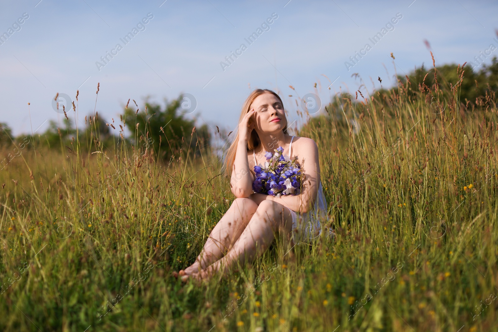 Beautiful woman with bouquet of wildflowers enjoying sunny day in meadow Photo of Beautiful woman with bouquet of wildflowers enjoying sunny day in meadow