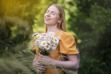 Photo of Happy woman with bouquet of wildflowers in forest