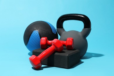 Photo of Medicine ball, kettlebell, foam block and dumbbells on light blue background