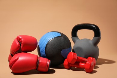 Photo of Medicine ball, dumbbells, kettlebell and boxing gloves on beige background