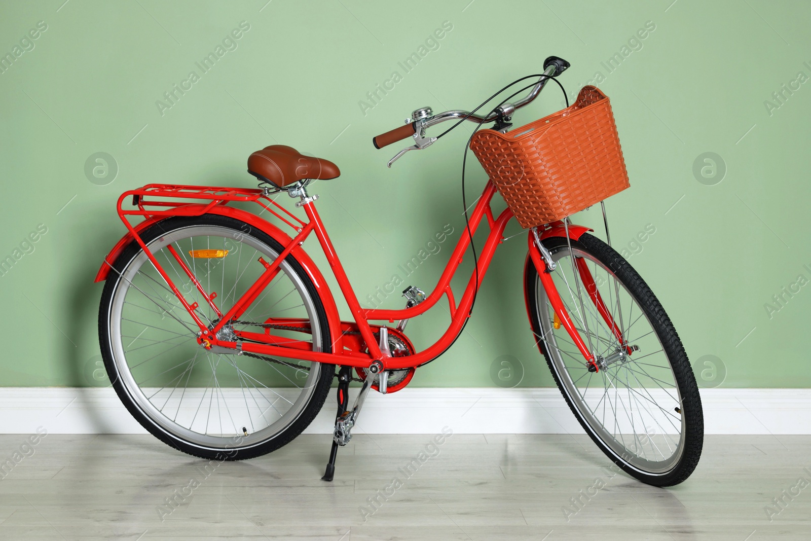 Red bicycle with basket near light green wall indoors Photo of Red bicycle with basket near light green wall indoors