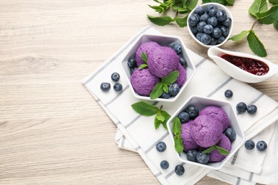Photo of Tasty sorbet with blueberries, mint and jam on wooden table, flat lay. Space for text