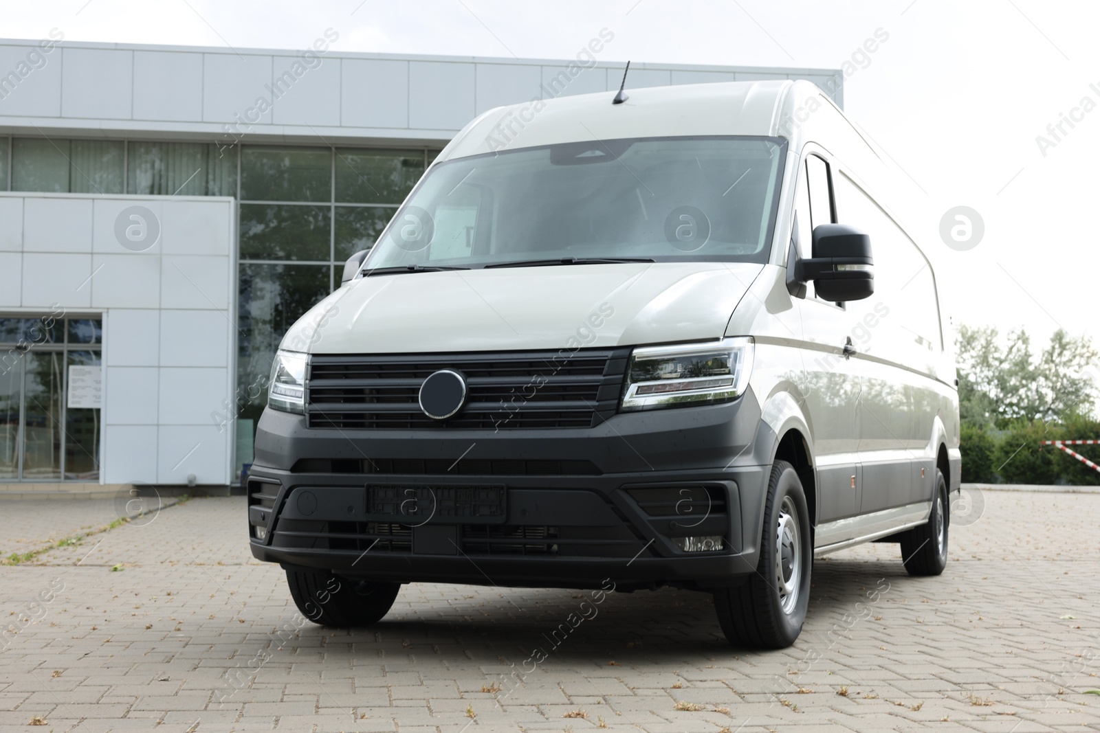 One white minibus parked on paved road outdoors Photo of One white minibus parked on paved road outdoors