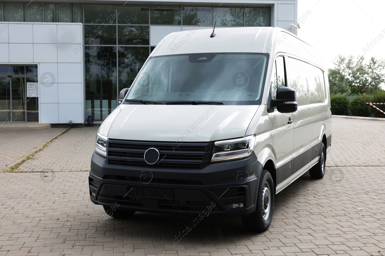 One white minibus parked on paved road outdoors Photo of One white minibus parked on paved road outdoors
