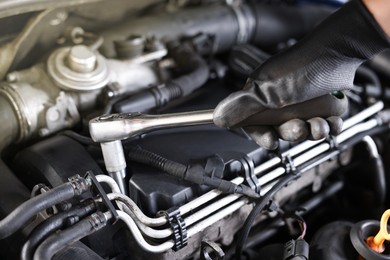 Photo of Auto parts. Professional mechanic with torque wrench fixing car indoors, closeup